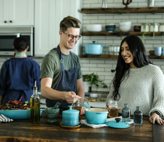 가정에서 실천하는 건강한 식습관 smiling man standing and mixing near woman in kitchen area of the house