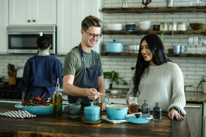 Photo by Odiseo Castrejon smiling man standing and mixing near woman in kitchen area of the house
