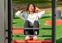 유산소 운동과 근력 운동의 균형 맞추기 woman in white long sleeve shirt and black pants sitting on red metal frame