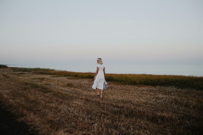Photo by Timothy Tarasov woman walking on brown grass field