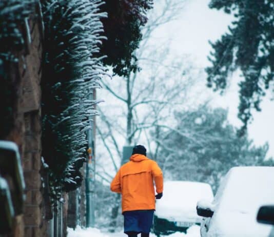 심장병 예방을 위한 스트레스 관리법 person in orange hoodie walking on snow covered pathway during daytime