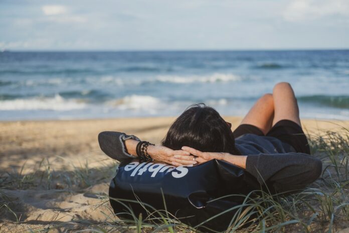 Photo by Dan Burton woman lying on grass front of sea at daytime