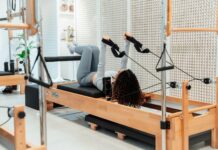 필라테스, 건강한 몸과 마음을 만들어주는 웰빙 운동의 열풍 a woman is doing exercises on a rowing machine