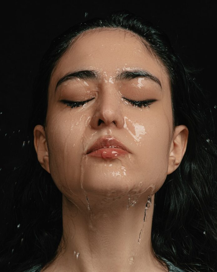 a woman with her eyes closed covered in water