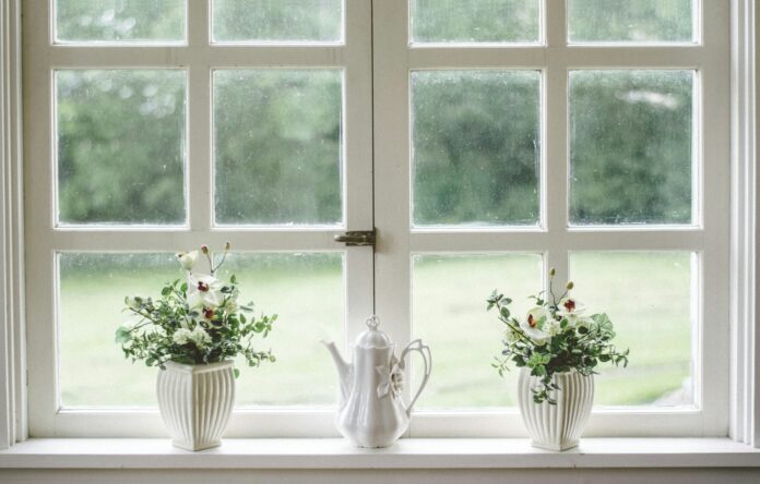 Photo by Nathan Fertig white teapot and tow flower vases on windowpane